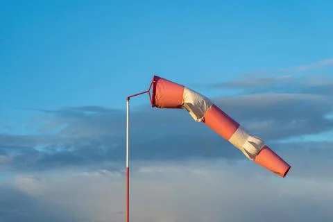 Red and white wind indicator in the shape of a cone at the airfield. Sunset a Stock Photos