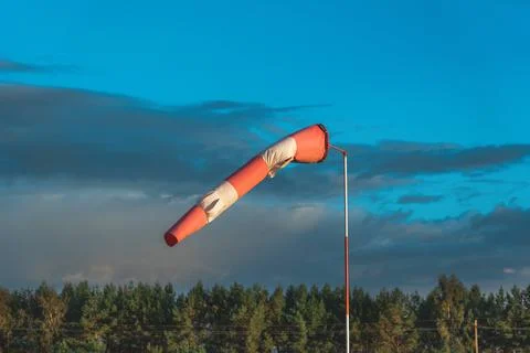 Red and white wind indicator in the shape of a cone at the airfield. Forest i Stock Photos