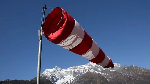 Red and white wind sock blowing with Himalaya Mountain peaks in background Stock-Footage 101444092