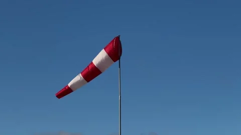 Red and white windsock against a clear blue sky in the background Stock Footage 294036943