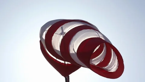 Red and white windsock blowing in wind with sun shining through lens flare Stock Footage 101443759