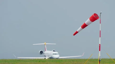 Red and white windsock blowing in wind at airport 库存影片 334346094