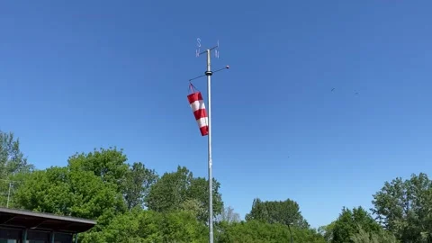 Red and white windsock blowing in the wind against blue sky background. Video stock 338275521