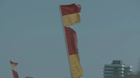 Red and Yellow Beach Flags Fluttering Near High-Rise Buildings Sunshine Coast Au Stock Footage 341285316