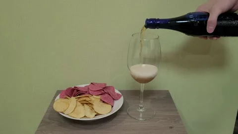 Red and yellow chips. Snacks on a plate. Pouring beer into a glass. Stock Footage 231696860