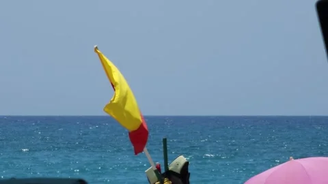 Red and yellow flag on beach indicating swim area Perfect for beach and safety Stock Footage 277796546