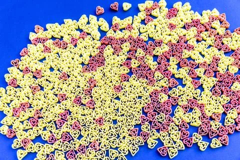 Red and yellow heart shaped pasta on blue background 스톡 사진