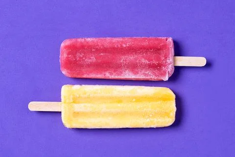 Red and yellow popsicles pattern on purple background Stock Photos