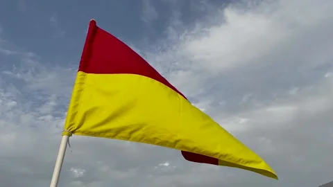 Red and yellow warning flag on the beach flutters in the wind Stock Footage 239157345