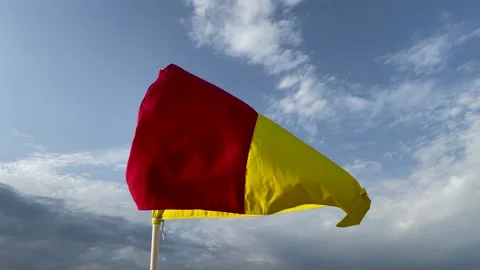 Red and yellow warning flag on the beach flutters in the wind Stock Footage 239827121