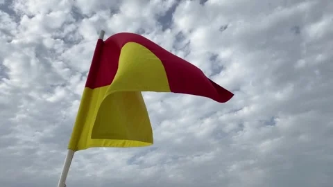 Red and yellow warning flag on the beach flutters in the wind Stock Footage 243370942