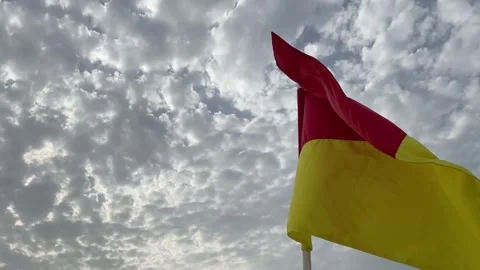 Red and yellow warning flag on the beach flutters in the wind Stock Footage 244482123