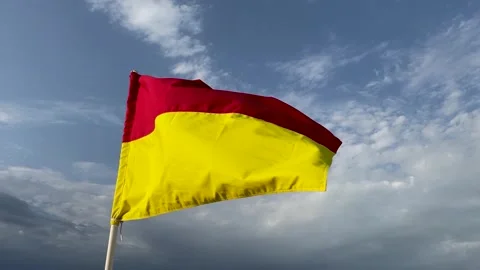 Red and yellow warning flag on the beach flutters in the wind Stock Footage 246976182