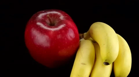 Red apple and bananas rotating with black background Stock Footage 54076243