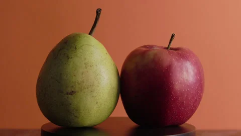 Red apple and green pear rotate on orange background Stock Footage 330687279