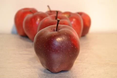 Red apple and a triangle of red apples in background. Stock Photos