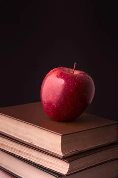 Red apple on book stack on black background Stock Photos