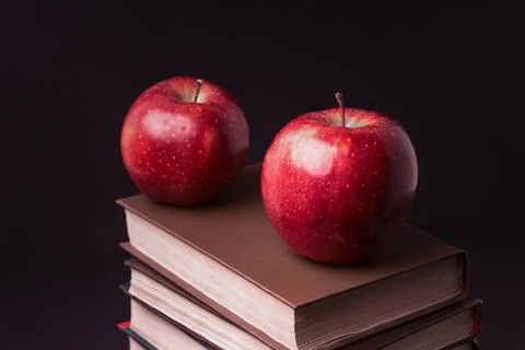 Red apple on book stack on black background Stock Photos