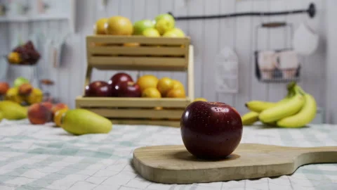 Red apple on cutting board with display filled with fruit behind it Stock Footage 341202688