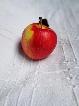 Red apple with dried leaf on textured white fabric background Stock Photos
