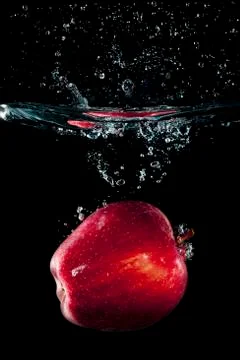 A red apple falling in water with a splash Stock Photos