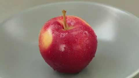 Red apple on grey plate. Camera moves down Stock Footage 80375311