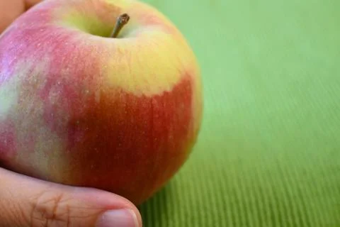 Red apple in hand on green background 库存照片