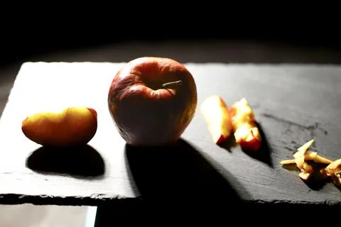 Red apple with a large bright slice placed on a slate board Stock Photos