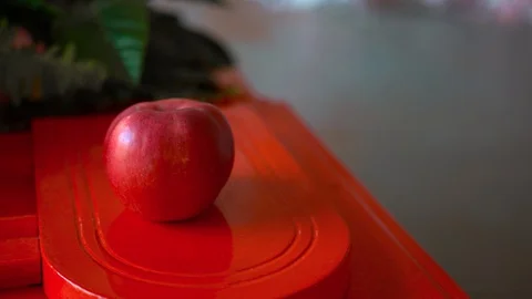 A red Apple lies on a red surface Stockbeeldmateriaal 127702848