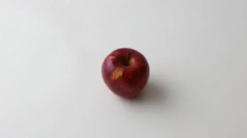 Red apple lies on a white plate on a white background Stock Footage