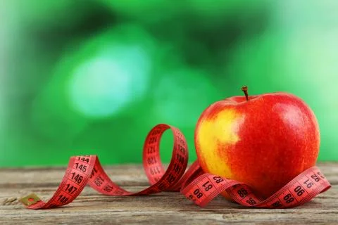 Red apple with measuring tape on grey wooden background Stock Photos