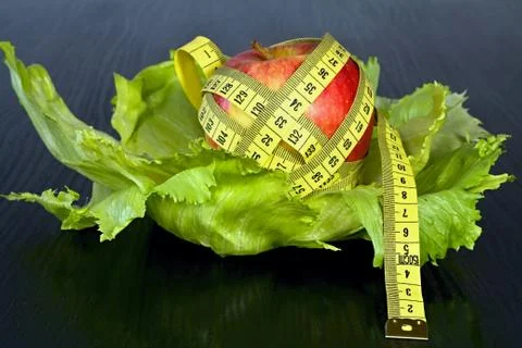 Red apple with measuring tape on a sheets of ice salad. Stock Photos