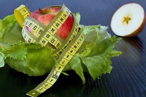 Red apple with measuring tape on a sheets of ice salad. Stock Photos