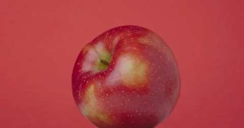 Red apple rotates hanging on a red background, isolated. Video stock 154953630
