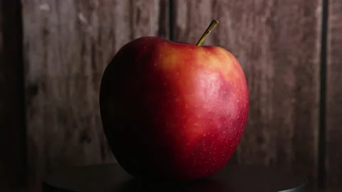 Red apple rotating around its axis on a brown wooden background Stock Footage 330687244