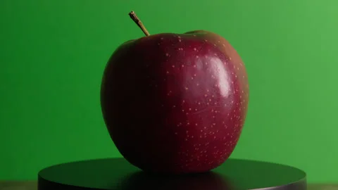 Red apple rotating around its axis on a green background Stock Footage 330687297