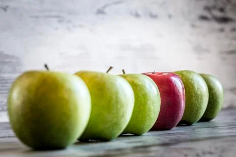 Red apple in a row of green apples Foto stock