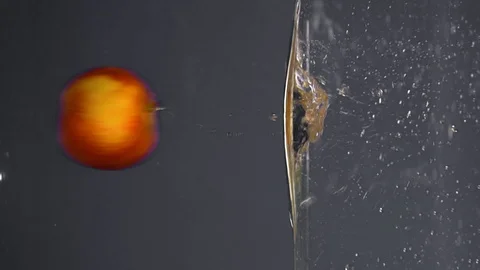 The red Apple in the spray falls into the water on a gray background, slow Stockbeeldmateriaal 102468880