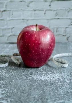 Red apple for weight loss while dieting, centimeter measuring tape, on gray Stock Photos