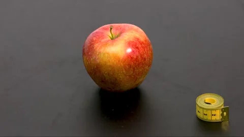 A red apple wrapped in a yellow tailor's measuring tape Stock Footage 184469731