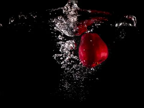 Red apple , yellow lemon falling into splashing water on black background Stock Photos
