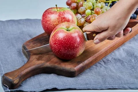 Red apples and grape bunches on a wooden board Stock Photos