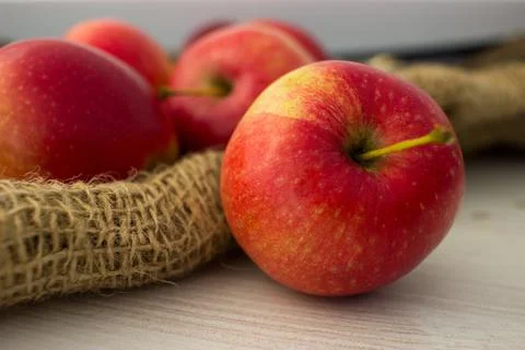 Red apples in burlap on the table Stock Photos