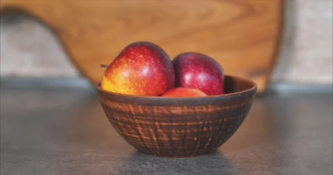 Red apples in a clay plate. In the background is a large cutting board made Stock Footage 254968600