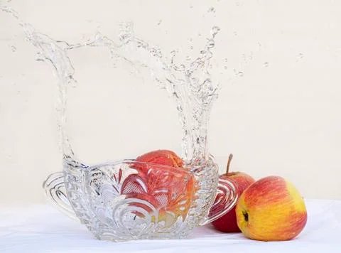 Red apples crystal vase and casting water on a white background Stock Photos