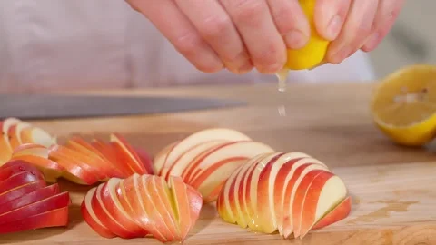 Red apples cut into thin slices are poured with lemon juice on a wooden board Stock Footage 267011251