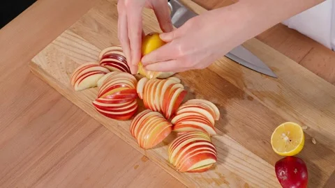 Red apples cut into thin slices are poured with lemon juice on a wooden board Stock Footage 267011269
