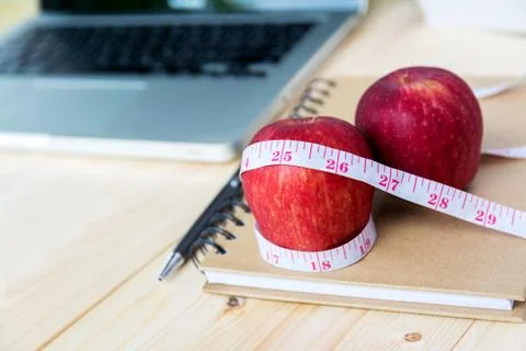 Red apples with measuring tape on notebook Stock Photos