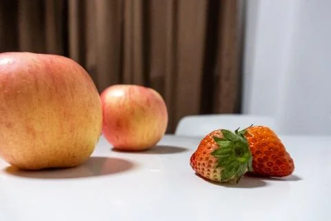 Red apples with strawberries on white table closeup Stock Photos