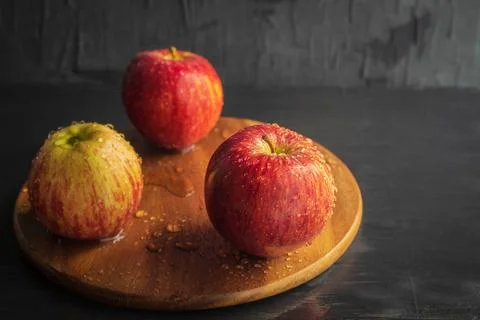 Red apples with water elements lie on a wooden round board Foto stock